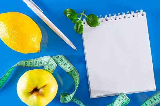 Blank notebook, fruits and measuring tape on a blue background photo