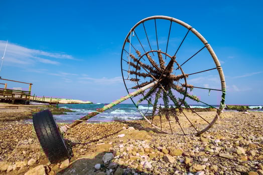 Abandoned beach umbrella on a rocky beach set against the sea photo