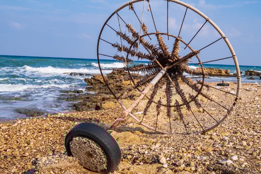 Abandoned beach umbrella on a rocky beach set against the sea photo