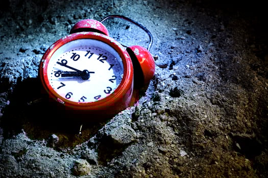 Red retro style alarm clock lying in ashes under the bright spotlight photo