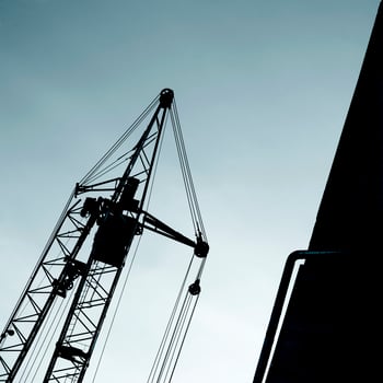 Backlit view of a lifting crane photo