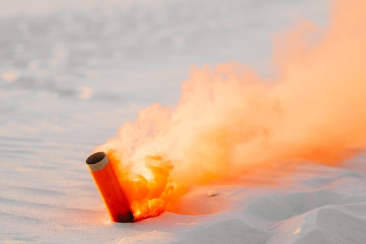 Smoke bomb with orange smoke stuck in the sand photo