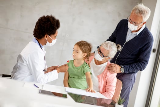 Doctor examining young girl with grandparents present photo