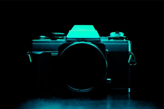 Low key image of a vintage film camera in turquoise color photo