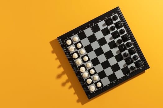 Top view of chess board with pieces on yellow background photo