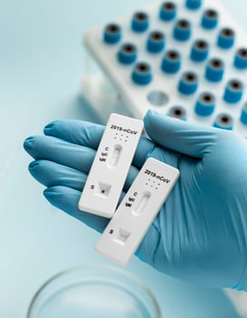 Hand with protective gloves holding covid tests photo