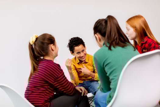 Portrait of cute little kids in jeans  talking and sitting in chairs against white wall photo