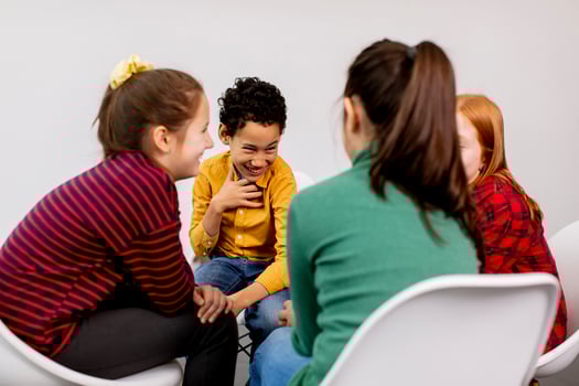 Portrait of cute little kids in jeans  talking and sitting in chairs against white wall photo