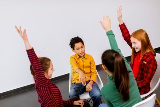 Portrait of cute little kids in jeans  talking and sitting in chairs against white wall photo