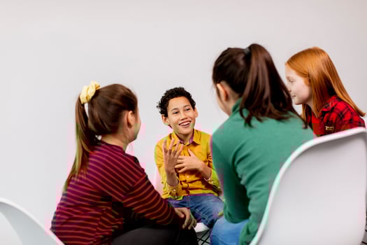 Portrait of cute little kids in jeans  talking and sitting in chairs against white wall photo
