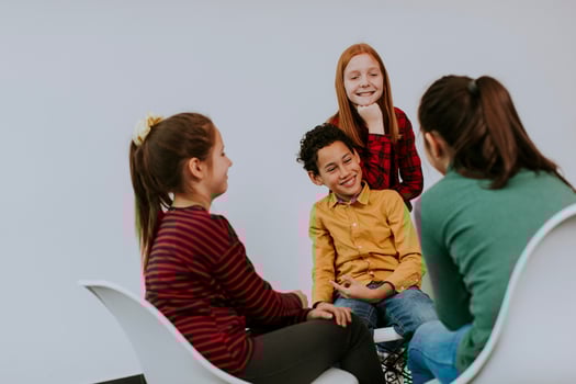 Portrait of cute little kids in jeans  talking and sitting in chairs against white wall photo