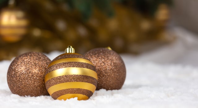 Three Christmas golden balls against background of a Christmas tree photo