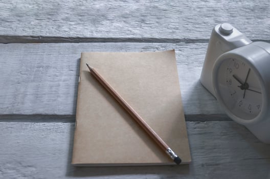 A book and pencil with alarm clock on an old wood table photo
