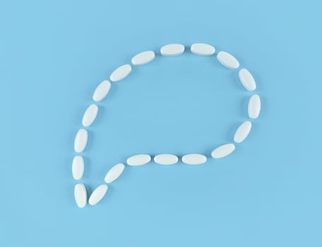 Speech bubble made from white tablets on blue backdrop with copy space photo
