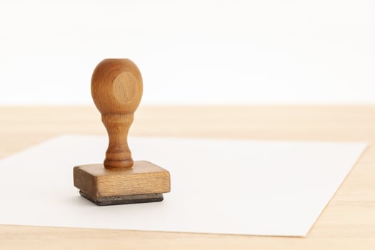 Vintage rubber stamp and blank paper on wooden table photo