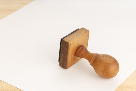 Vintage rubber stamp and blank paper on wooden table photo
