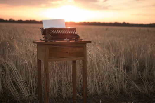 typewriter on a walnut bedside table in a wheat field at sunset photo