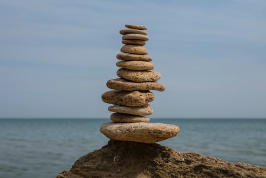 balancing pyramid of stones on a large stone on the seashore photo