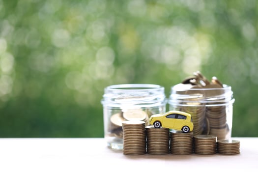 Miniature car model on growing stack of coins money on nature green background photo