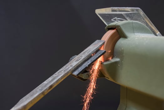 master sharpens a chisel on a grinding machine photo