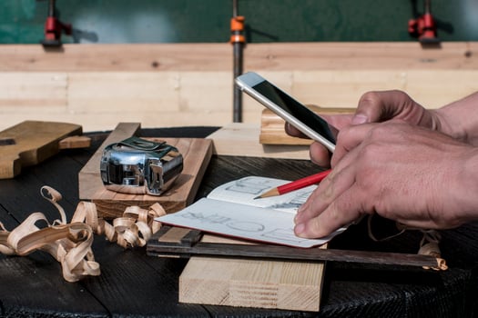 carpenter in the workshop with a red pencil looking at the blueprints photo