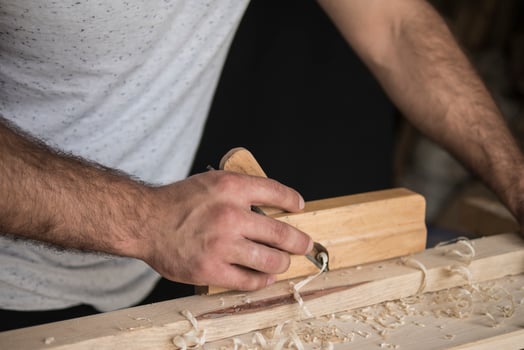 carpenter in a white T shirt stroking with a plane photo