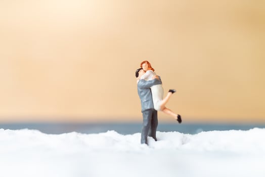 Miniature people, happy wedding couple on a white beach, wedding concept photo