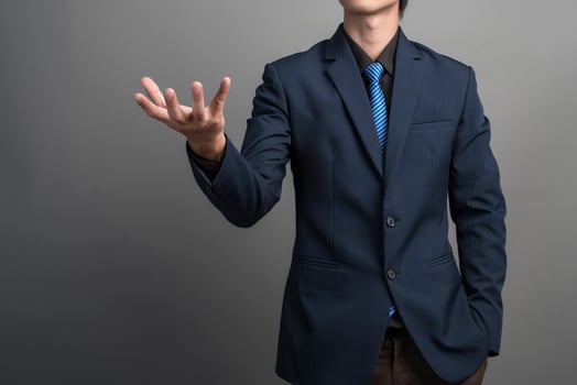Close up of businessman in blue suit holding something on gray background photo