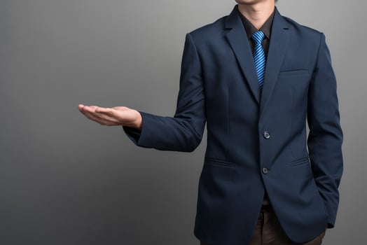 Close up of businessman in blue suit holding something on gray background photo