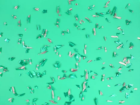 Confetti foil pieces on green background. Abstract festive backdrop. photo