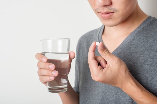 Man taking a pill on white background photo