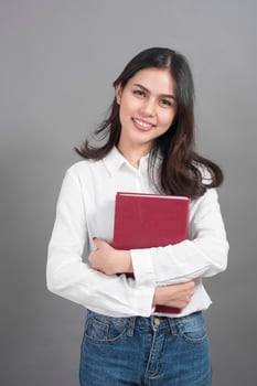 Portrait of woman University student holding book in studio grey background photo