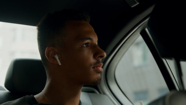 Young man sitting in back of cab putting ear phones in photo