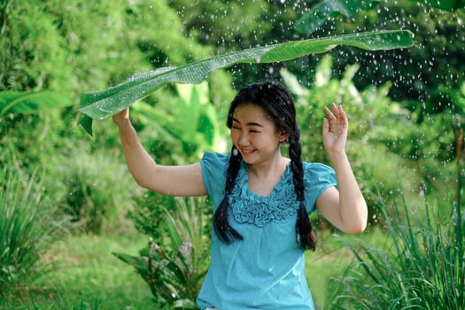 Young Asia woman was under a banana leaf taking shelter from the rain in the green garden background photo