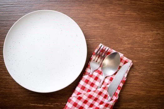 Empty plate or dish with knife, fork, and spoon on wood tile background photo