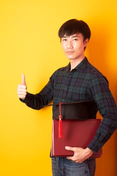 University man is happy with graduation on yellow background photo