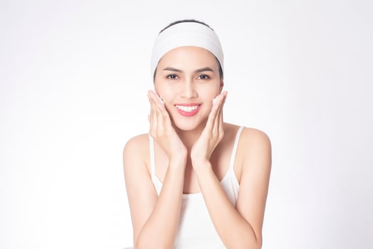 Beautiful woman is washing her face on white background photo