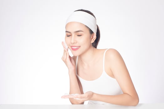 Beautiful woman is washing her face on white background photo