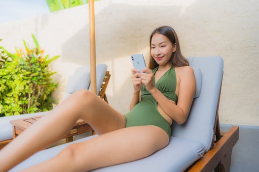 Portrait beautiful young asian woman sitting on the chair deck with umbrella neary swimming pool photo