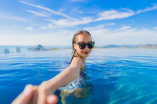 Portrait beautiful young asian woman smile happy relax around swimming pool in hotel resort with sea and ocean view photo