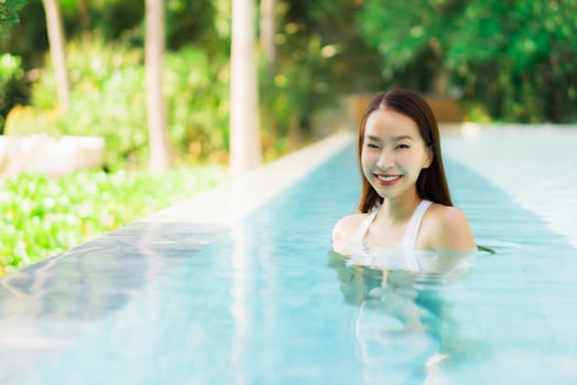 Portrait beautiful young asian woman happy smile in swimming pool around resort and hotel photo