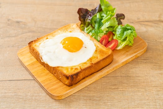 Homemade bread toasted with cheese and fried egg on top with vegetable salad for breakfast photo
