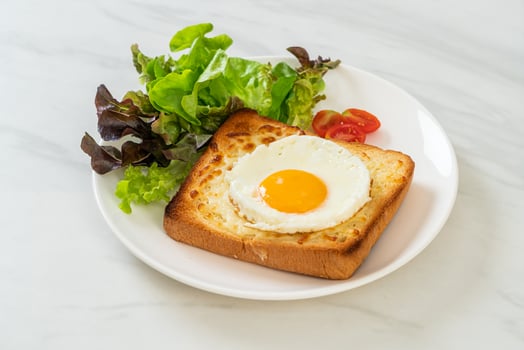 Homemade bread toasted with cheese and fried egg on top with vegetable salad for breakfast photo