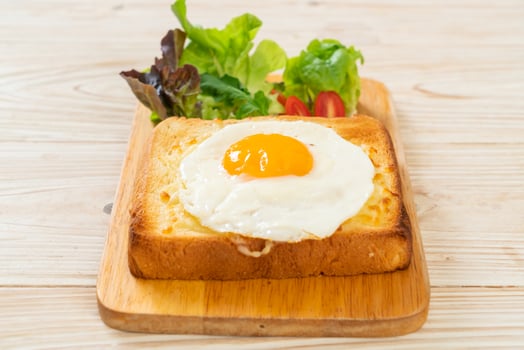 Homemade bread toasted with cheese and fried egg on top with vegetable salad for breakfast photo