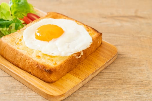 Homemade bread toasted with cheese and fried egg on top with vegetable salad for breakfast photo