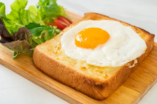 Homemade bread toasted with cheese and fried egg on top with vegetable salad for breakfast photo