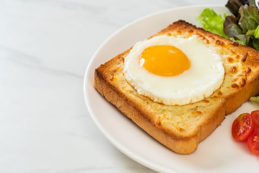 Homemade bread toasted with cheese and fried egg on top with vegetable salad for breakfast photo