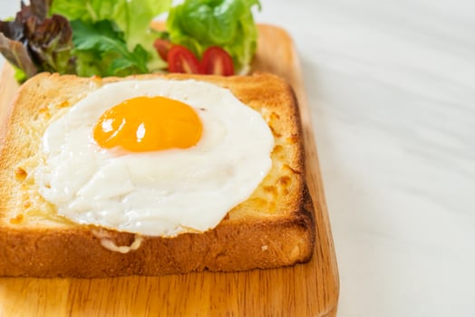 Homemade bread toasted with cheese and fried egg on top with vegetable salad for breakfast photo