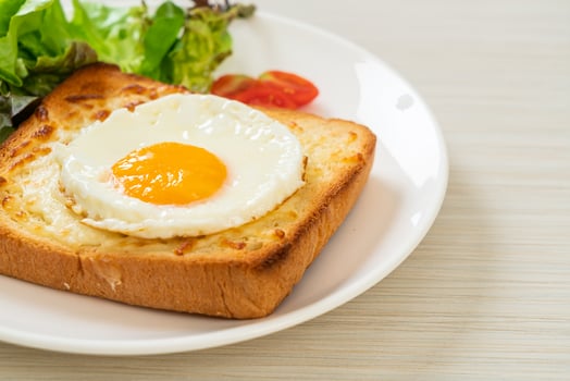 Homemade bread toasted with cheese and fried egg on top with vegetable salad for breakfast photo