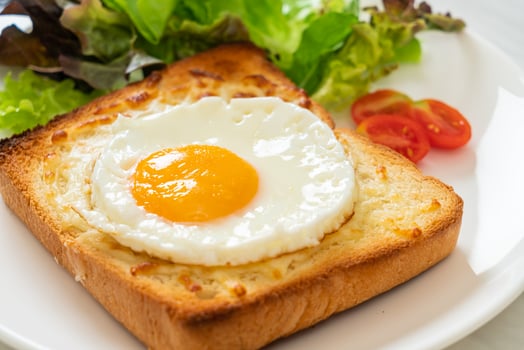 Homemade bread toasted with cheese and fried egg on top with vegetable salad for breakfast photo